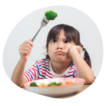 Child holding a fork with green vegetable on it, looking disgruntled